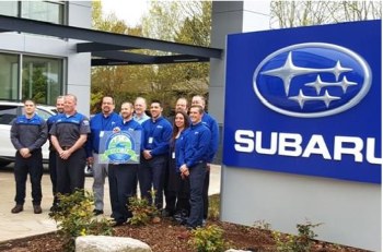 group of people receiving award next to a Subaru sign