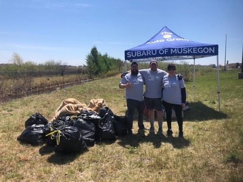 group of Subaru employees standing near bags of trash