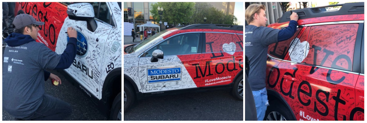 signing a wrapped Subaru Outback for charity